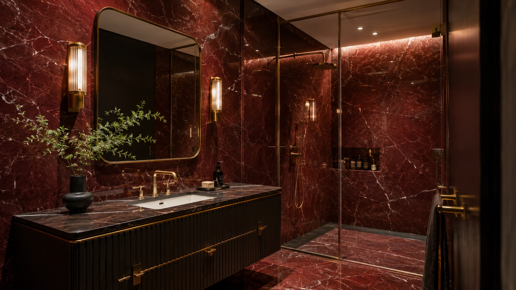 Floor to ceiling red marble statement bathroom with brass fixtures and moody accent lighting
